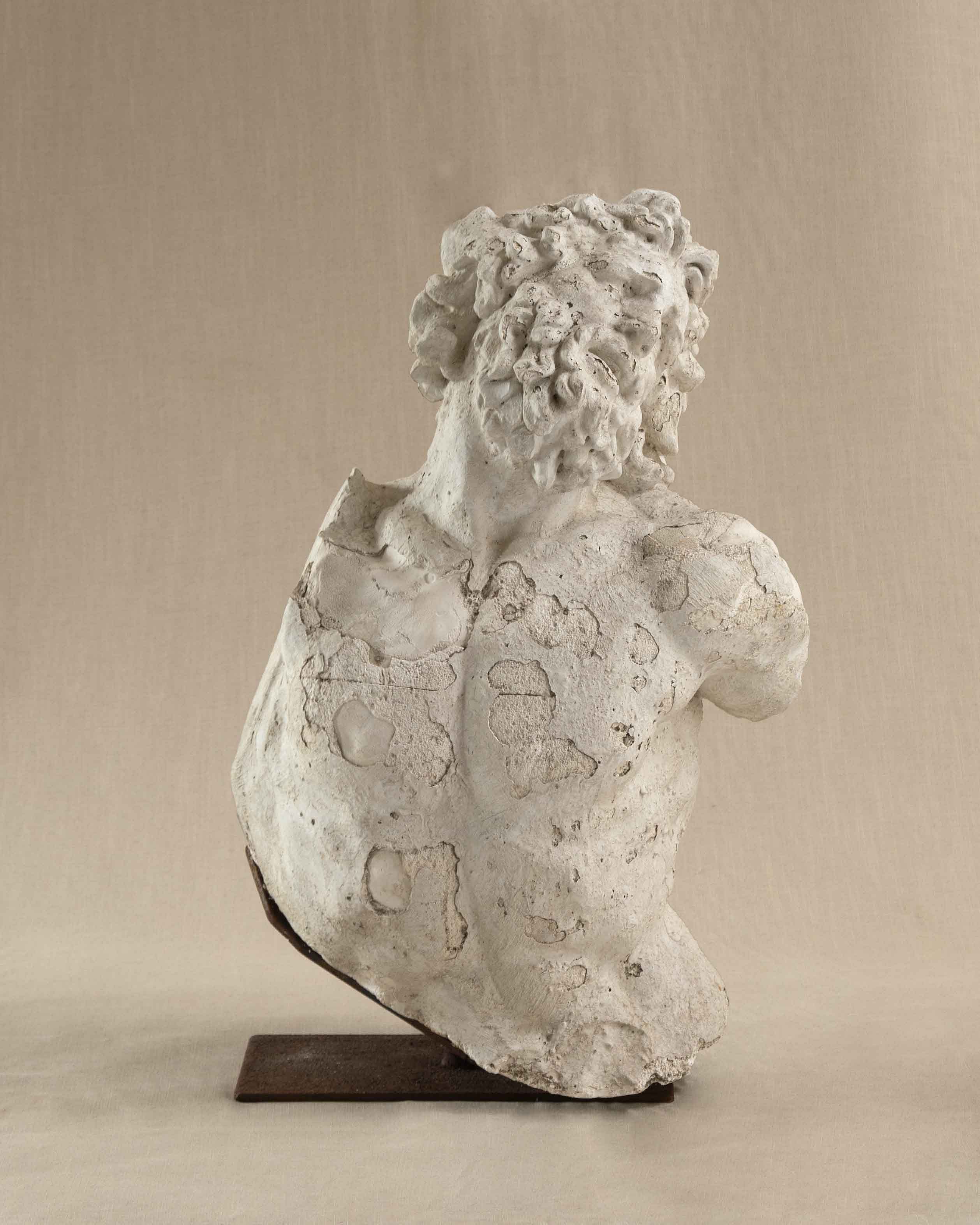 A large plaster bust on a beige linen backdrop.