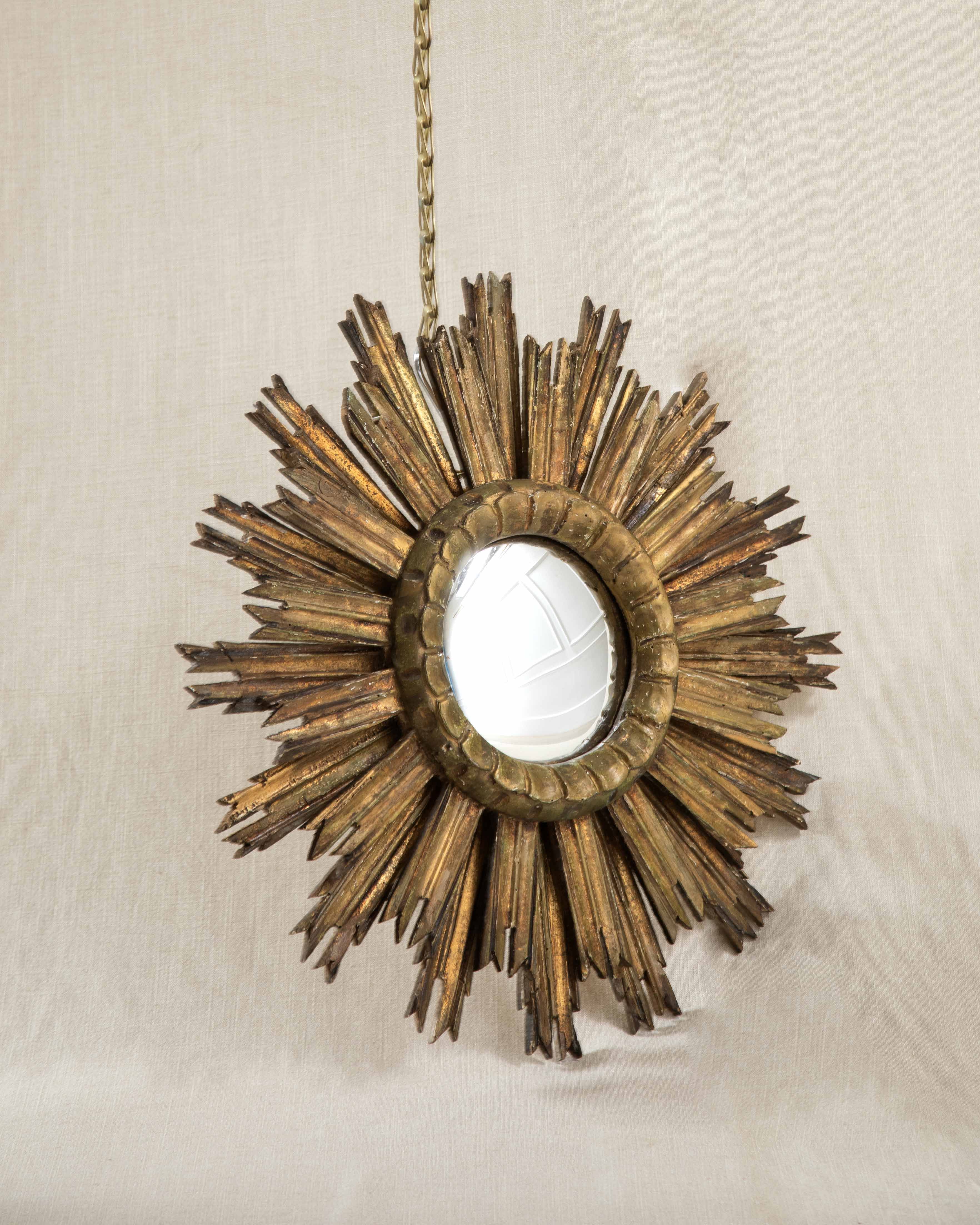 An antique wall mirror on a beige linen backdrop.